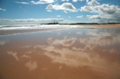 White clouds and blue sky reflected in wet sands of Embleton Beach, Northumberland on a beautiful sunny day